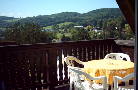 Tisch mit vier Stühlen auf Holzbalkon mit Blick auf die fränkische Schweiz